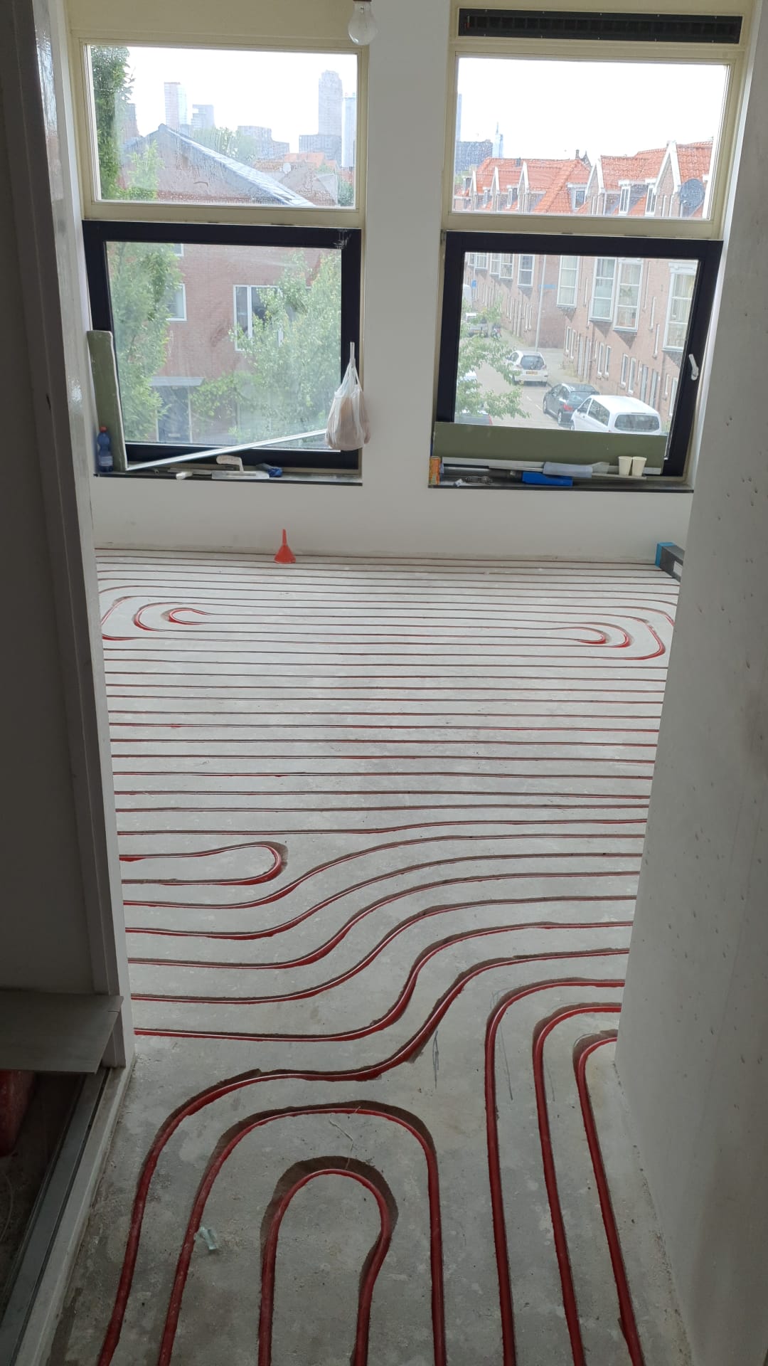 Ingefreesde vloerverwarming in een lichte woonkamer met uitzicht over de daken